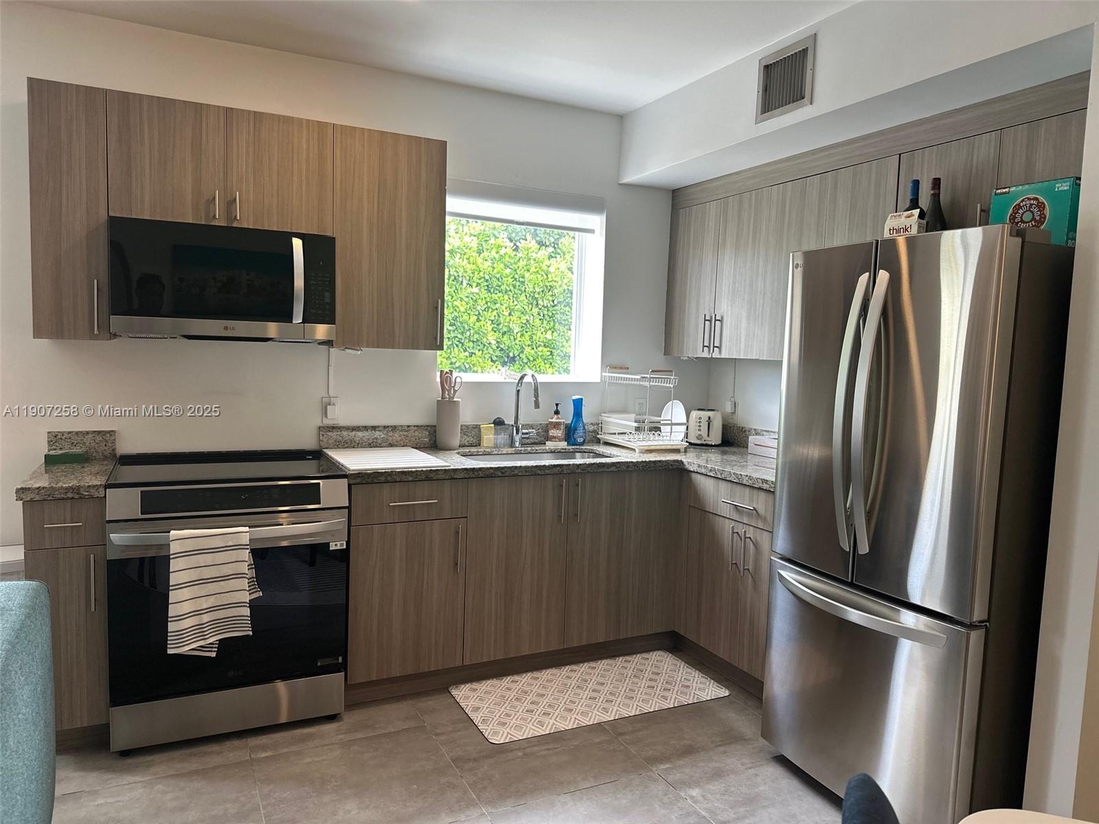 165 Northwest 39th Street, Unit 4 Miami, FL 33127 - Photo 5 of 11 a kitchen with a refrigerator stove and microwave