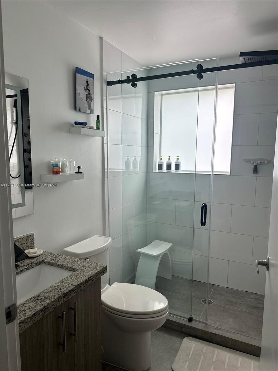 165 Northwest 39th Street, Unit 4 Miami, FL 33127 - Photo 6 of 11 a bathroom with a granite countertop sink toilet and shower