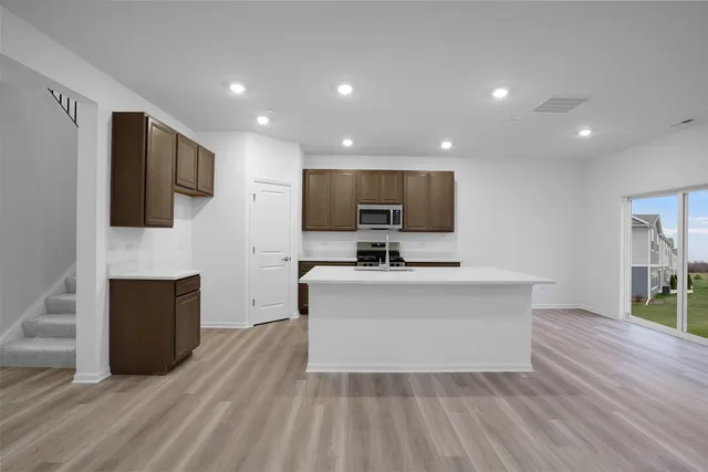 a view of living room kitchen with stainless steel appliances wooden floor and large window