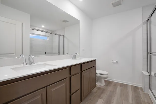 a bathroom with a double vanity sink toilet and a mirror