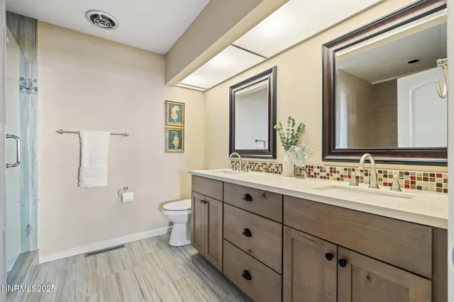a bathroom with a double vanity sink toilet and a mirror