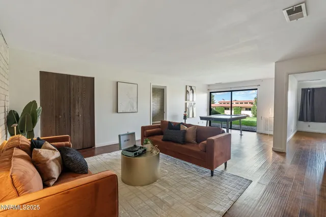 a living room with furniture a wooden floor and a potted plant