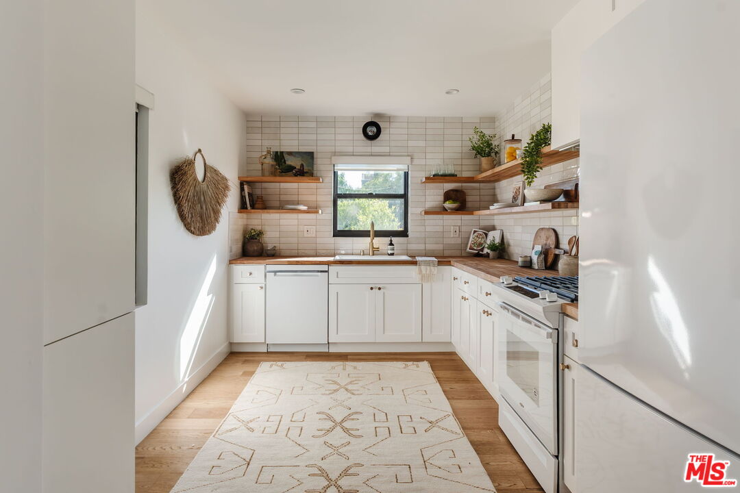 1943 12th, Unit B Santa Monica, CA 90404 - Photo 29 of 37 a kitchen with granite countertop white cabinets and white appliances