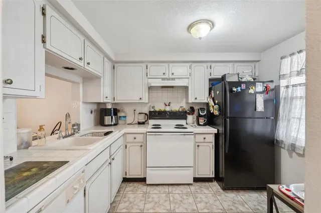 a kitchen with a sink a refrigerator and cabinets