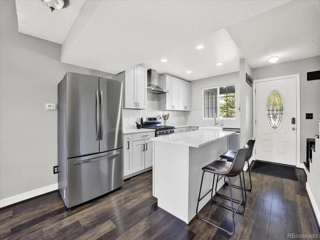 a kitchen with stainless steel appliances granite countertop a refrigerator a stove a sink dishwasher and a refrigerator with wooden floor