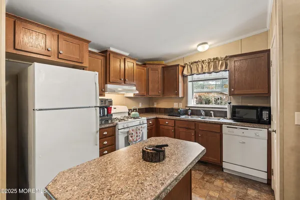 a kitchen with granite countertop a refrigerator stove top oven and sink