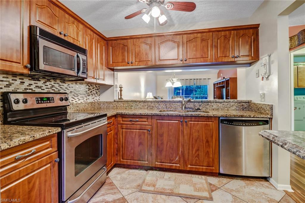 5675 Whitaker Road, Unit B202 Naples, FL 34112 - Photo 9 of 26 a kitchen with stainless steel appliances granite countertop a stove microwave and cabinets