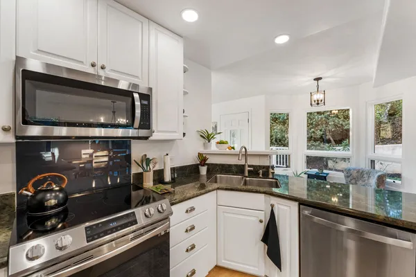 a kitchen with stainless steel appliances granite countertop a stove a sink and a microwave