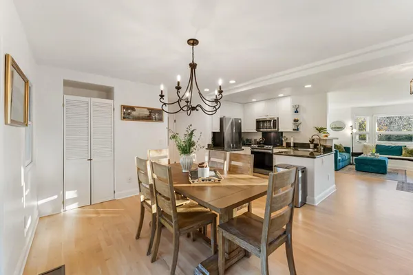 a view of a dining room and livingroom with furniture wooden floor a chandelier