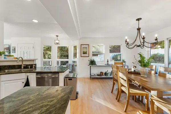 a dining hall with stainless steel appliances granite countertop a dining table chairs and chandelier