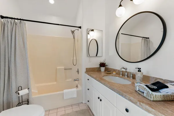 a bathroom with a granite countertop sink a toilet and shower