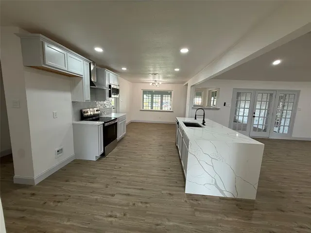 a large kitchen with stainless steel appliances granite countertop a large counter top and a wooden floors