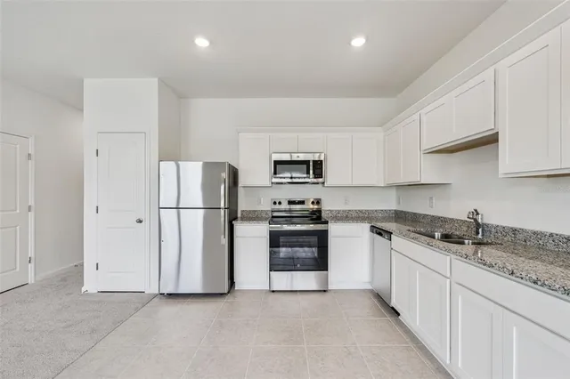 a kitchen with white cabinets and stainless steel appliances