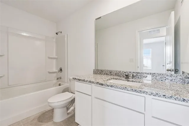 a bathroom with a granite countertop sink a toilet and bathtub