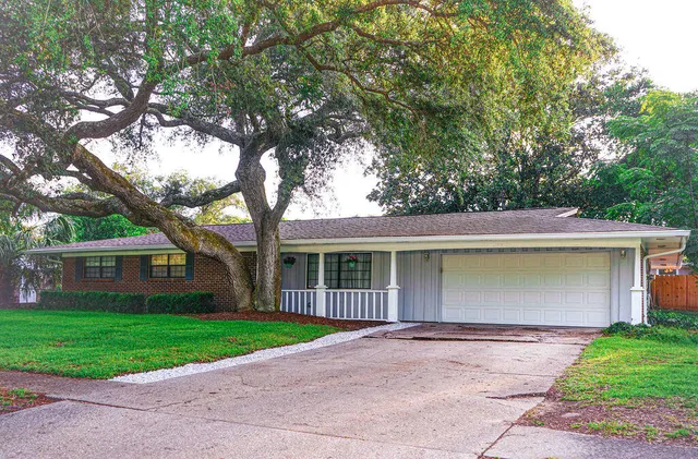 a front view of a house with a garden and trees