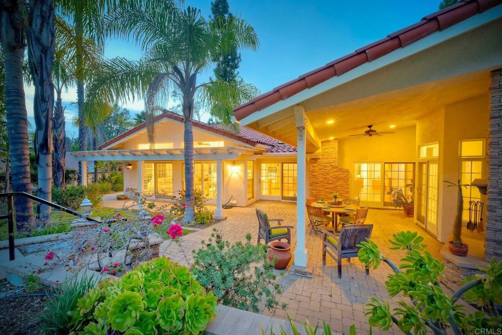 Twilight photo - backyard showing all the windows and sliding doors, covered patio, lush landscaping