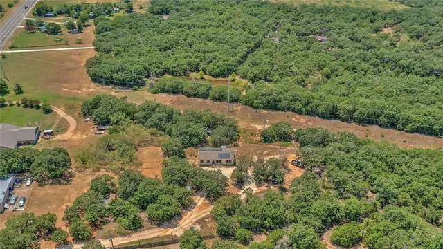 an aerial view of residential house with outdoor space and trees all around