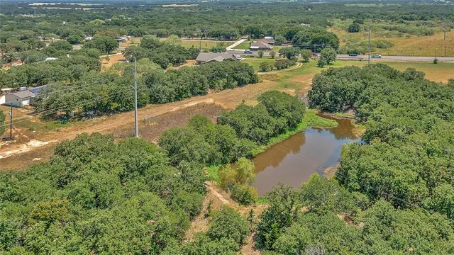an aerial view of residential houses with outdoor space and trees