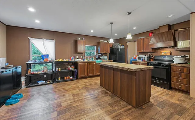 a kitchen with stainless steel appliances kitchen island granite countertop a stove top oven a sink dishwasher a dining table and chairs with wooden floor