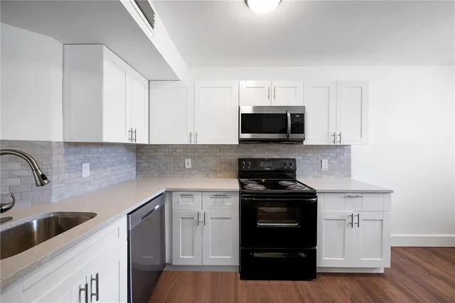 a kitchen with white cabinets and black appliances