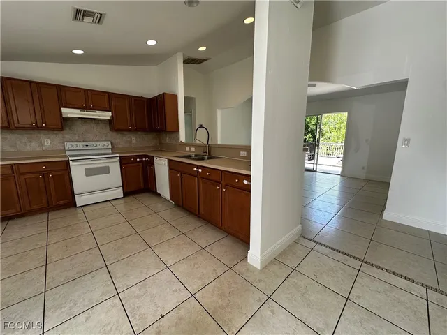 a large kitchen with stainless steel appliances granite countertop a stove a sink and a refrigerator