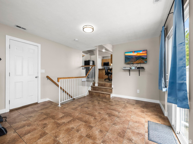 392 West Bricker Road Draper, UT 84020 - Photo 13 of 33 Spacious room featuring tile flooring, a white paneled door, and access to a multi-level staircase with wood handrails and white balusters