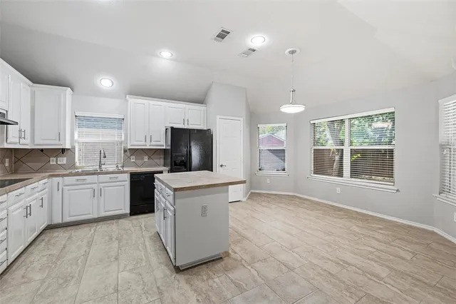 a large kitchen with stainless steel appliances granite countertop a stove a sink dishwasher and a refrigerator with white cabinets