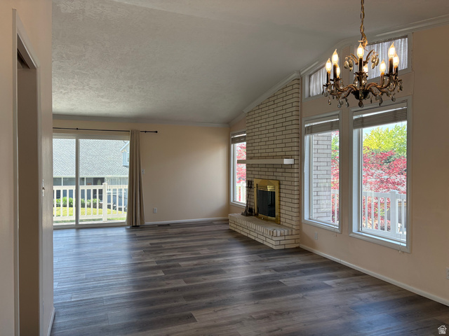 595 Meadowlark Road Orem, UT 84097 - Photo 10 of 87 Vaulted ceiling living area featuring wood-finish flooring, a brick fireplace with a golden firebox, multiple windows, and a sliding glass door