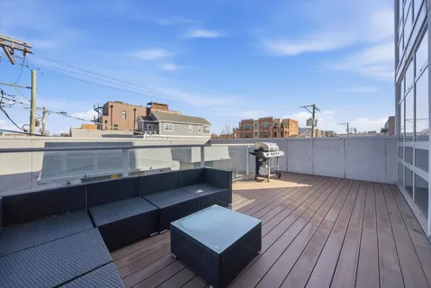 a view of a rooftop deck with couch and wooden floor
