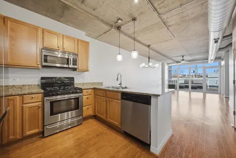 a kitchen with stainless steel appliances kitchen island granite countertop a stove and a wooden floors