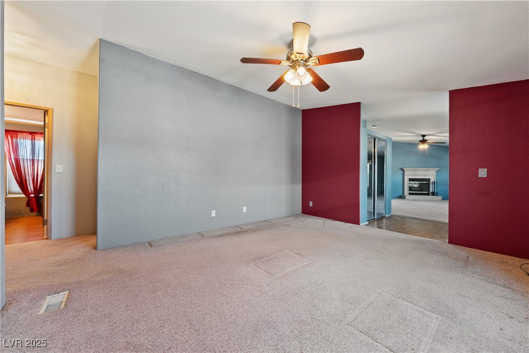 1391 East Casey Road Pahrump, NV 89048 - Photo 15 of 40 Empty room with ceiling fan, carpet flooring, and a glass covered fireplace