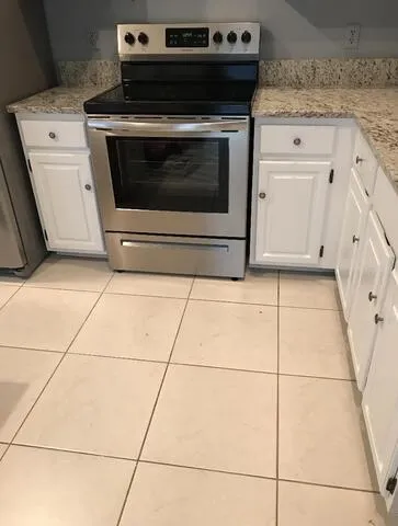 a kitchen with kitchen island granite countertop stainless steel appliances a sink a counter space and cabinets