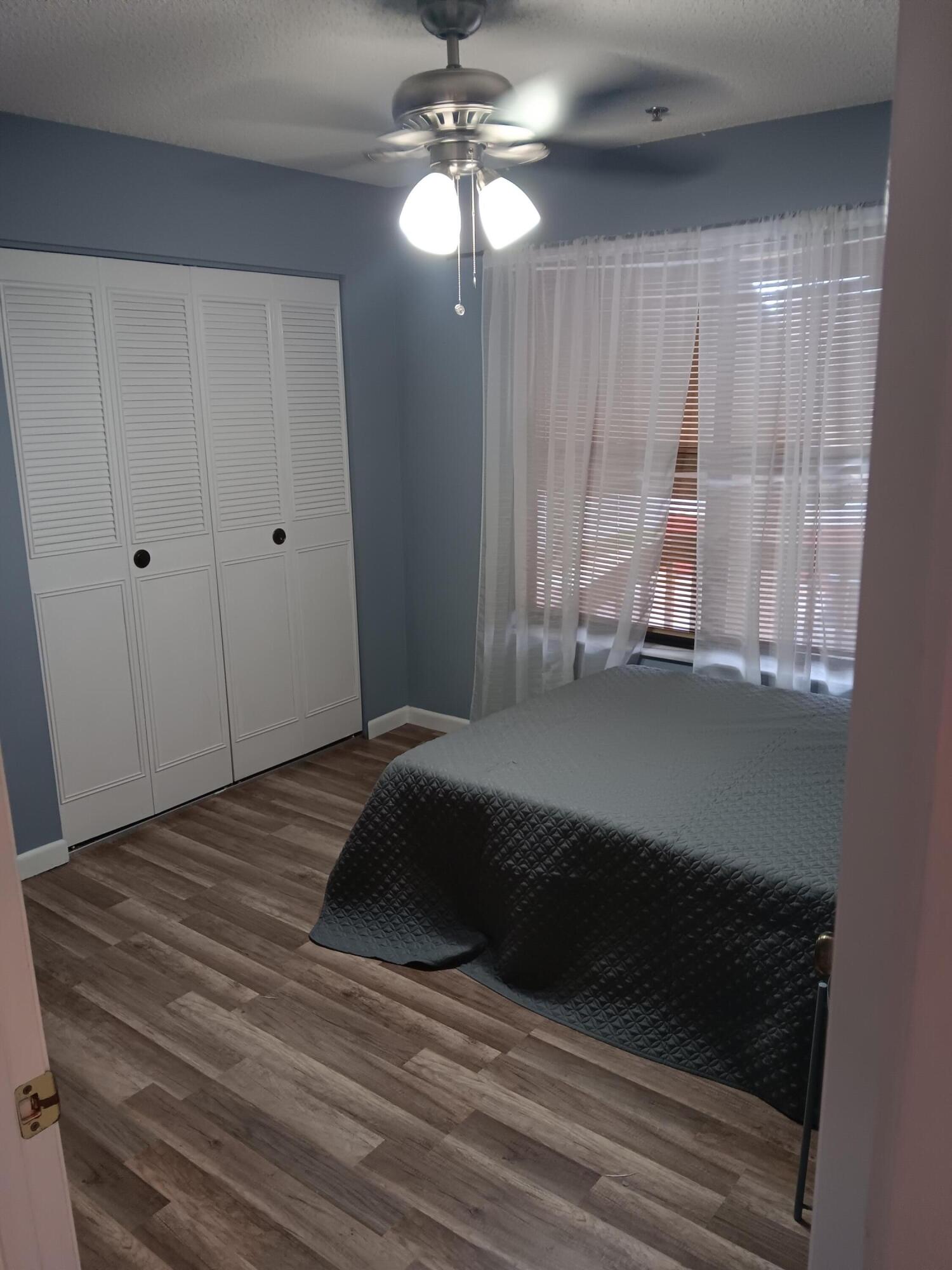 12989 Odessa Trail, Unit 3 Wellington, FL 33414 - Photo 21 of 32 a bedroom with a bed and a chandelier