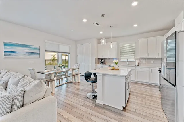 a kitchen with stainless steel appliances granite countertop a sink a stove a dining table and chairs