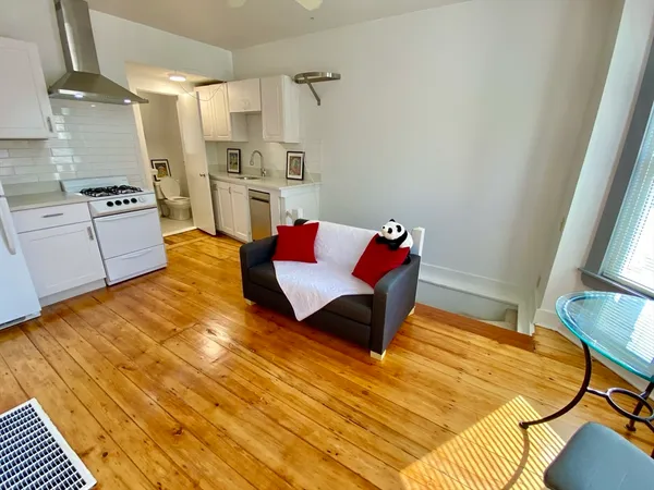 a living room with stainless steel appliances furniture and a kitchen view
