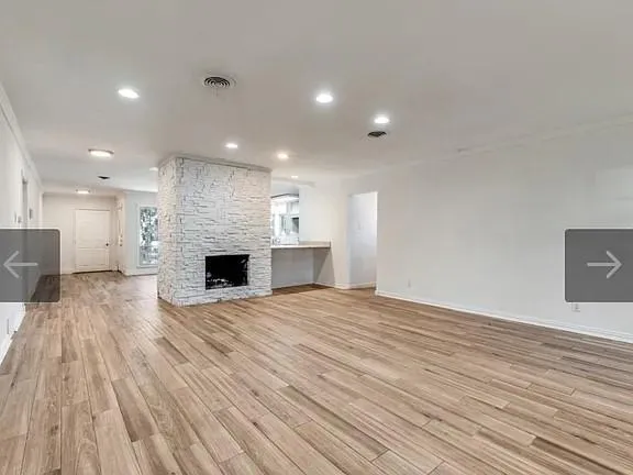 a view of empty room with wooden floor and fireplace