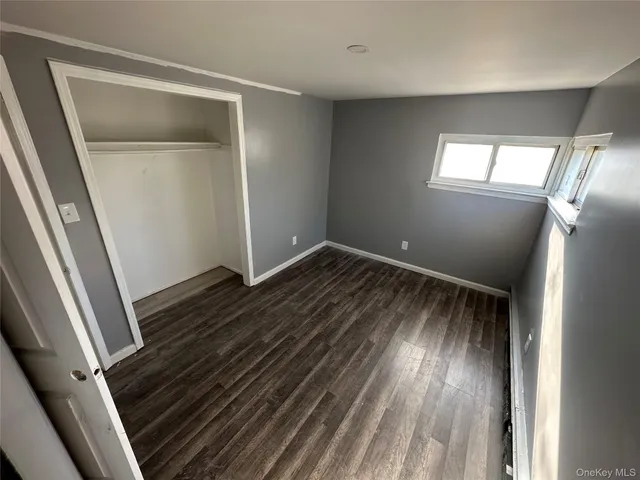 a view of an empty room and wooden floor and a window