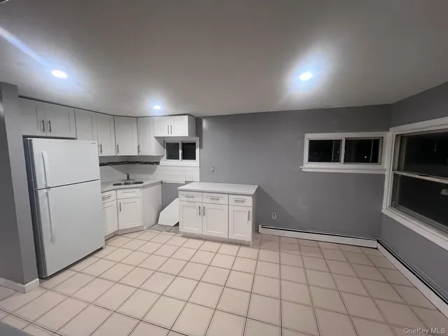 a kitchen with white cabinets a sink a stove a refrigerator and white cabinets