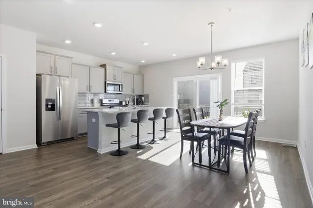 a kitchen with stainless steel appliances a dining table chairs stove refrigerator and cabinets