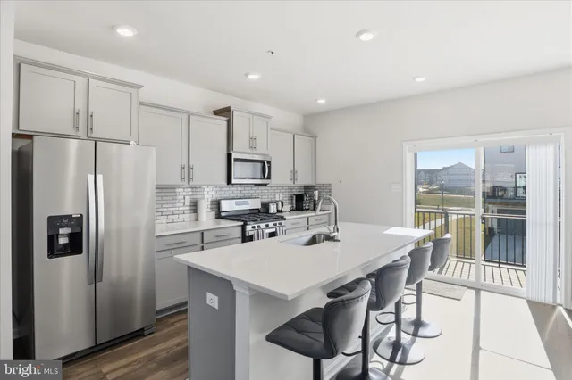 a kitchen with stainless steel appliances a refrigerator a sink a stove a dining table and chairs