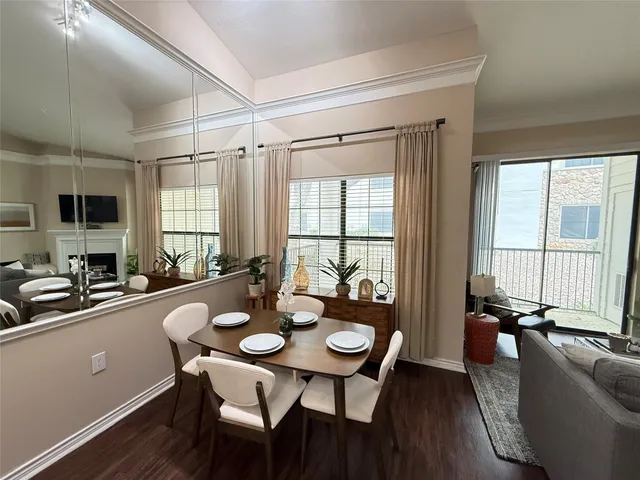 a view of a dining room and livingroom with furniture wooden floor a rug a flat screen tv a potted plant and a large window