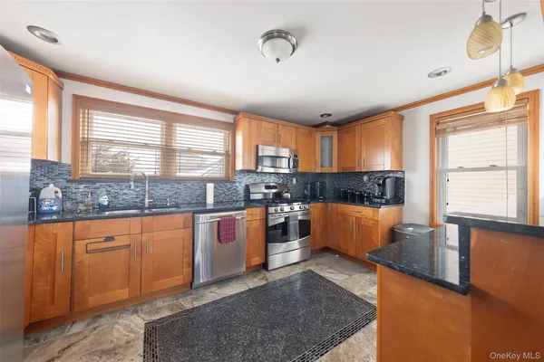 a large kitchen with granite countertop a stove a sink a window and stainless steel appliances