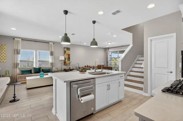 a kitchen with a stove a refrigerator a sink dishwasher with a dining table and chairs with wooden floor