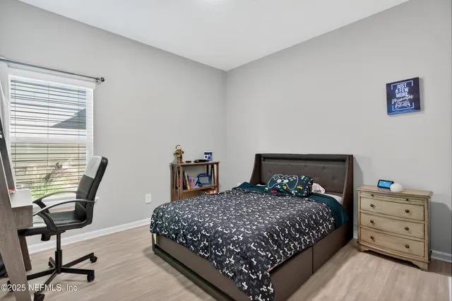 a bedroom with a bed a chair and a dresser next to a window