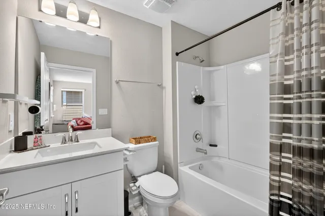 a bathroom with a bathtub shower sink vanity mirror and toilet