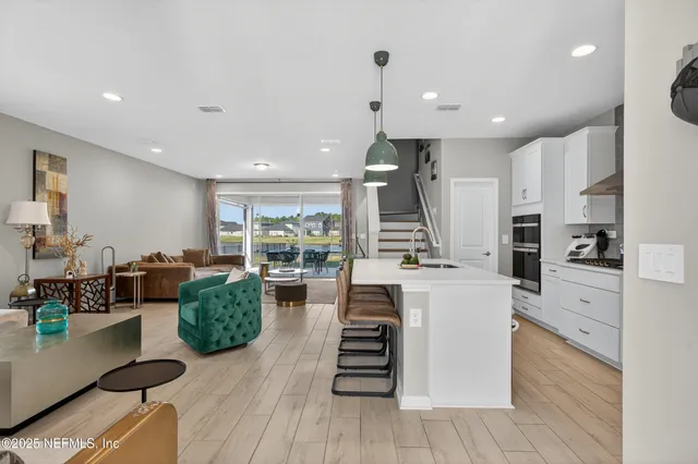 a large white kitchen with lots of counter space a sink and stainless steel appliances
