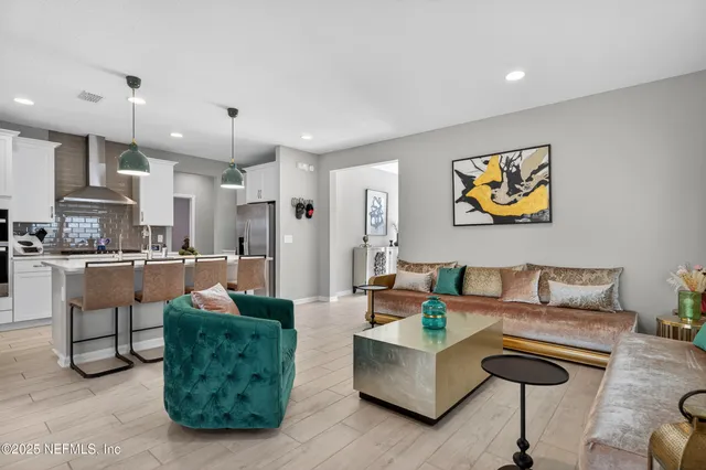 a living room with furniture kitchen view and a chandelier