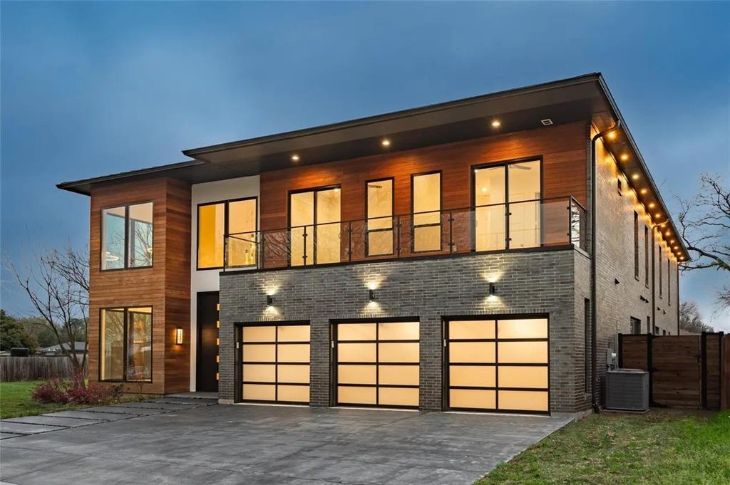 309 Kaye Street Coppell, TX 75019 - Photo 2 of 36 Modern exterior featuring wood paneling, dark brick accents, a three-car garage with frosted glass doors, a second-story balcony with glass railing, and a concrete drive