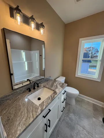a bathroom with a granite countertop sink a mirror and a toilet