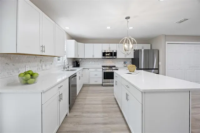 a kitchen with kitchen island granite countertop a sink a stove a refrigerator and a refrigerator